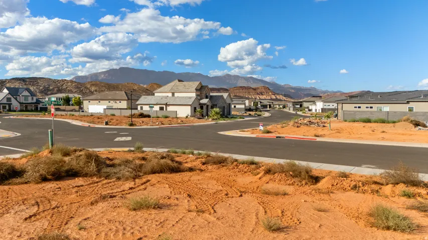 Mountain backdrop with a residential street, featuring multiple homes and undeveloped land