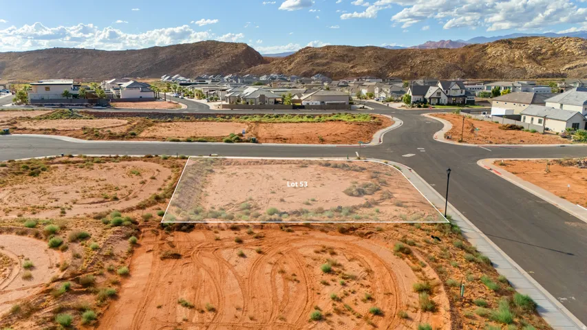 Corner lot with established street infrastructure, surrounded by a developing neighborhood, and mountain backdrop