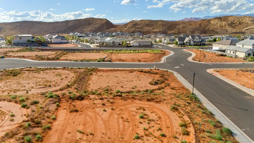 Graded residential lots with paved roads and integrated sidewalks, set against a backdrop of natural rock formations