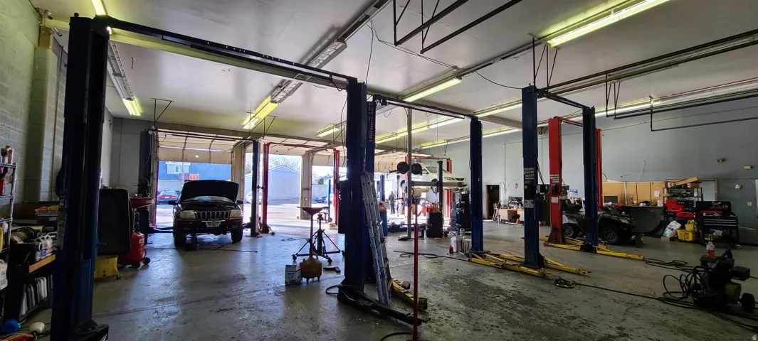 Commercial garage space featuring multiple vehicle lifts and overhead lighting