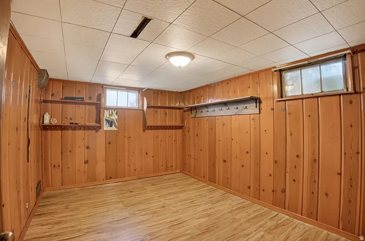 Wood-finish flooring, paneled walls, two windows, built-in shelving, and a flush mount ceiling light fixture