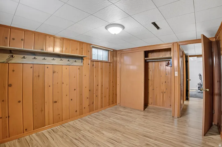 Wood-finish flooring, paneled walls, ceiling lighting, and built-in closet storage