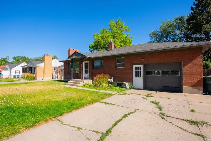 Brick exterior with a covered entry, attached garage, and a concrete driveway