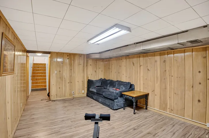 Finished lower level featuring wood-finish paneling, drop ceiling, and wood-finish flooring