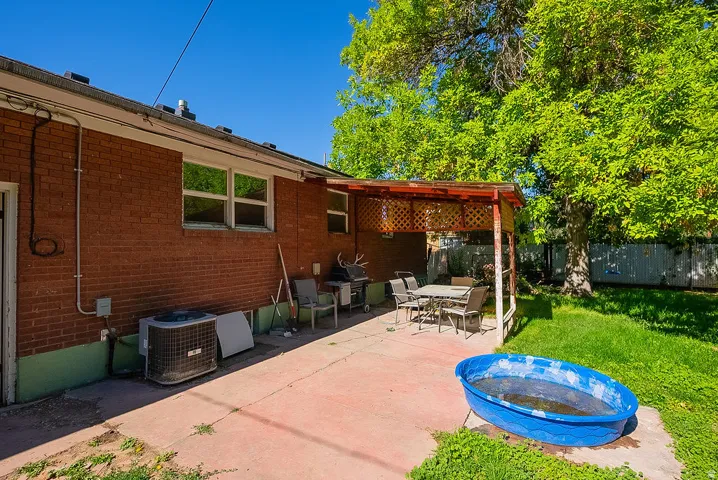 Brick exterior with multiple windows and an outdoor patio featuring a covered seating area
