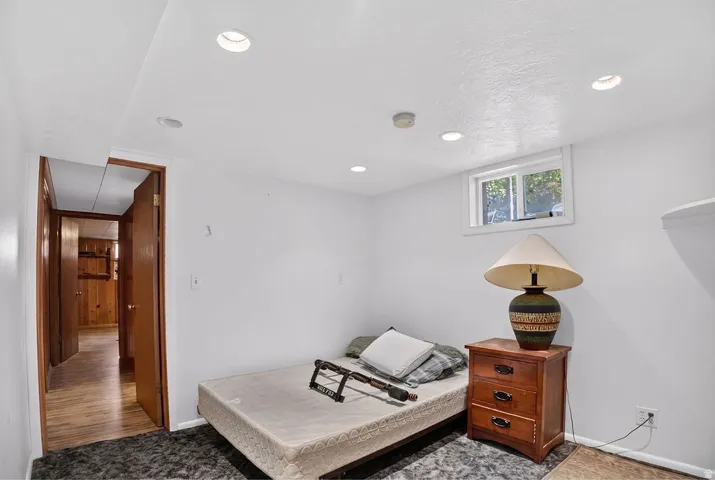 Recessed ceiling lighting, white painted walls, wood-finish interior door, and a window for natural light