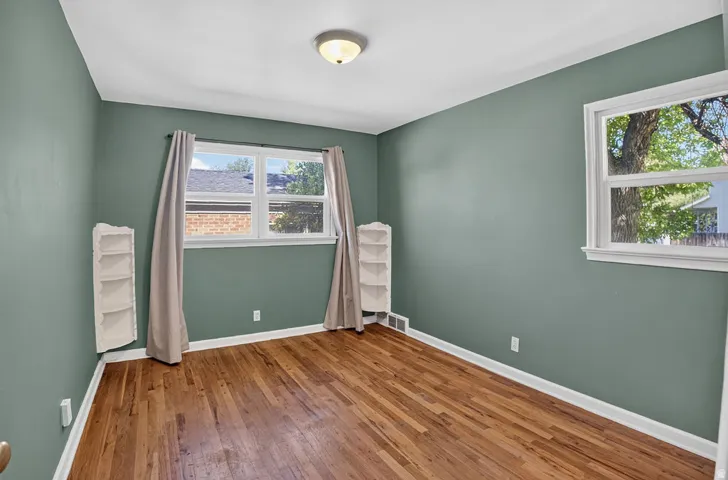 Hardwood flooring, painted walls, white trim, window with white frame, and a flush mount light fixture