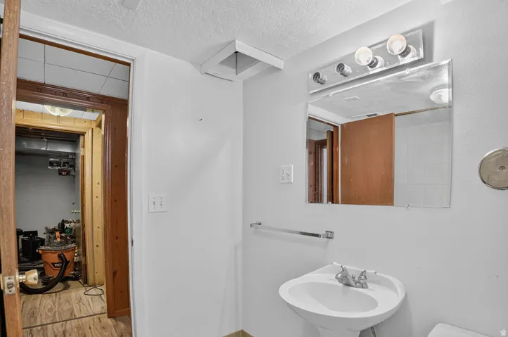 Pedestal sink with chrome faucet, wall-mounted mirror, and vanity light fixture
