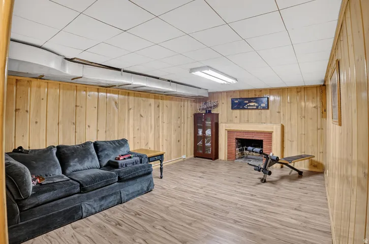 Wood-finish flooring with wood paneling walls and a drop ceiling