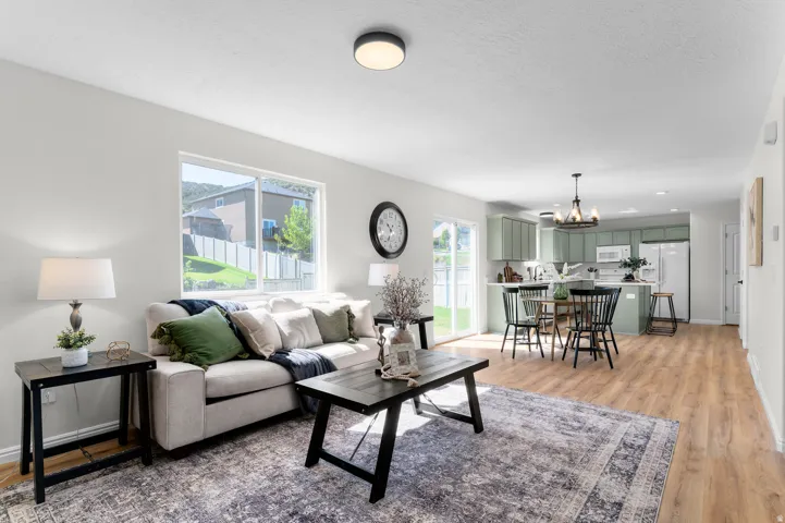 Open-concept living area featuring wood-finish flooring, a contemporary ceiling light fixture, and a sliding glass door