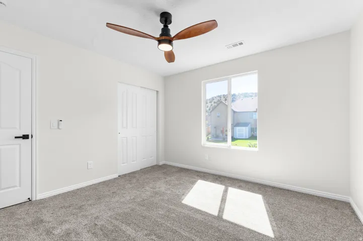 Plush carpeting, contemporary ceiling fan, dual-pane window, and white sliding closet doors