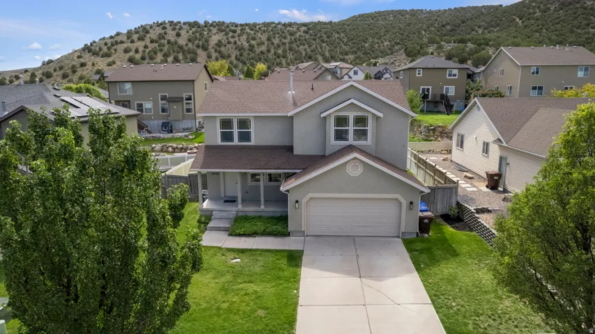 Two-story stucco home with a two-car garage, covered porch entry, and a manicured lawn