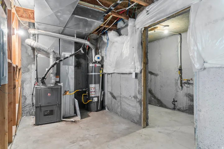 Concrete slab flooring, exposed wood framing, and a water heater