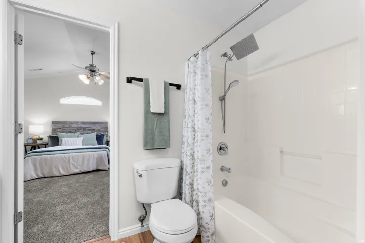 White bathtub with an integrated shower, featuring a rainfall showerhead and handheld sprayer