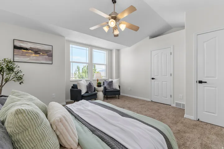 Vaulted ceilings with a ceiling fan, dual windows, and carpeted flooring