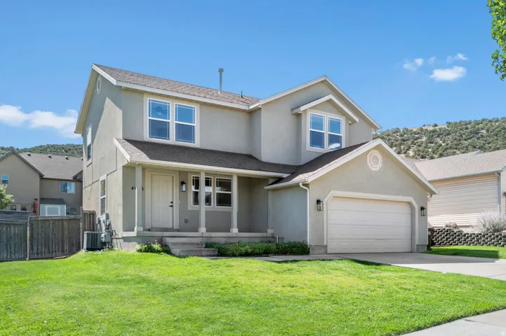 Stucco exterior with a covered front porch, attached garage, and landscaped front yard