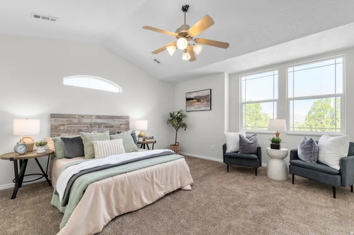 Vaulted ceiling with a ceiling fan, arched transom window, two large windows, and wall-to-wall carpeting