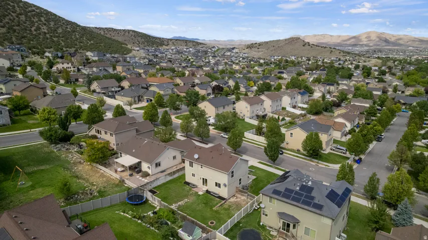 Residential neighborhood with multiple two-story homes, mature trees, and mountainous terrain in the background