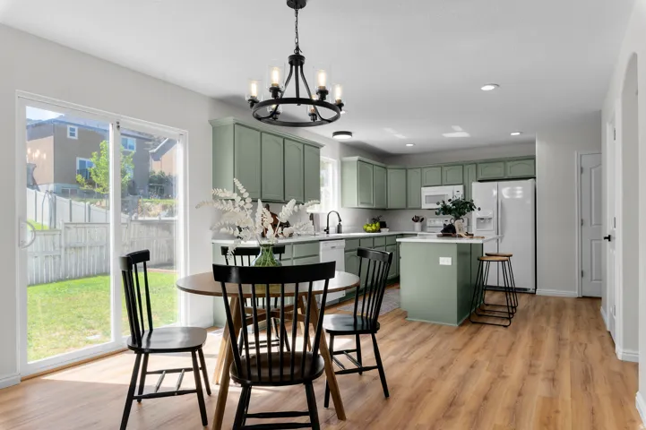 Kitchen featuring sage-toned cabinetry, a central island, and white appliances