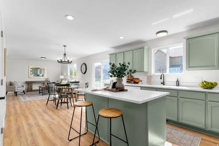 Kitchen island with white countertop, sage green cabinetry, wood-finish flooring, and recessed lighting