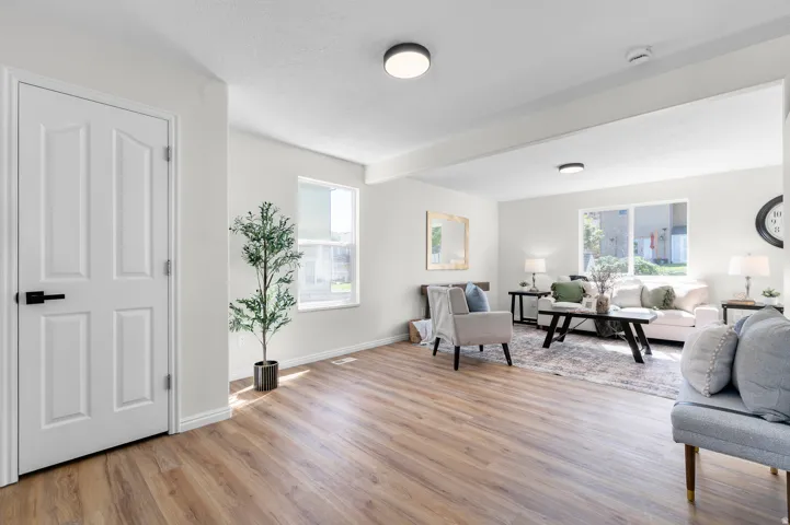 Wood-finish flooring throughout, white interior doors, multiple windows providing ambient light, and recessed ceiling lighting