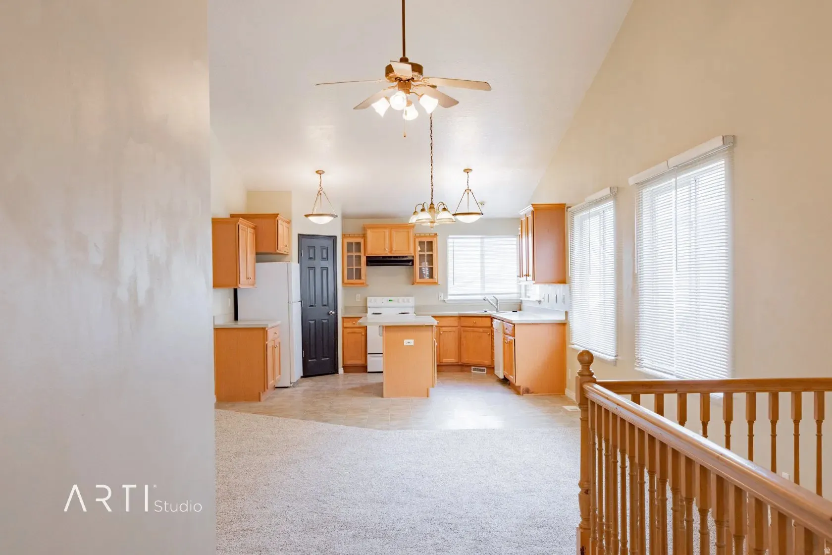 Vaulted ceiling with a ceiling fan light fixture, light wood-finish cabinetry, built-in kitchen island, multiple windows with blinds, and a wood-finish railing
