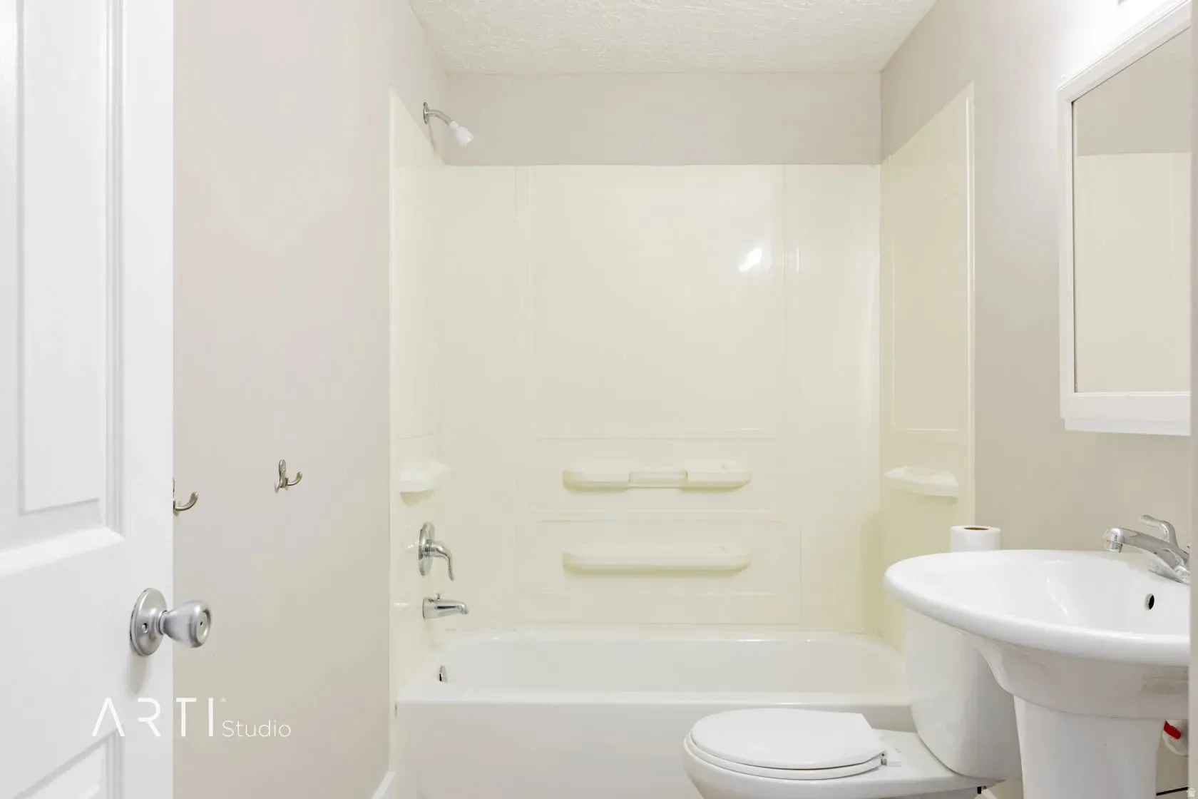 Bathtub with integrated shower, pedestal sink, wall-mounted mirror, and wall-mounted hooks
