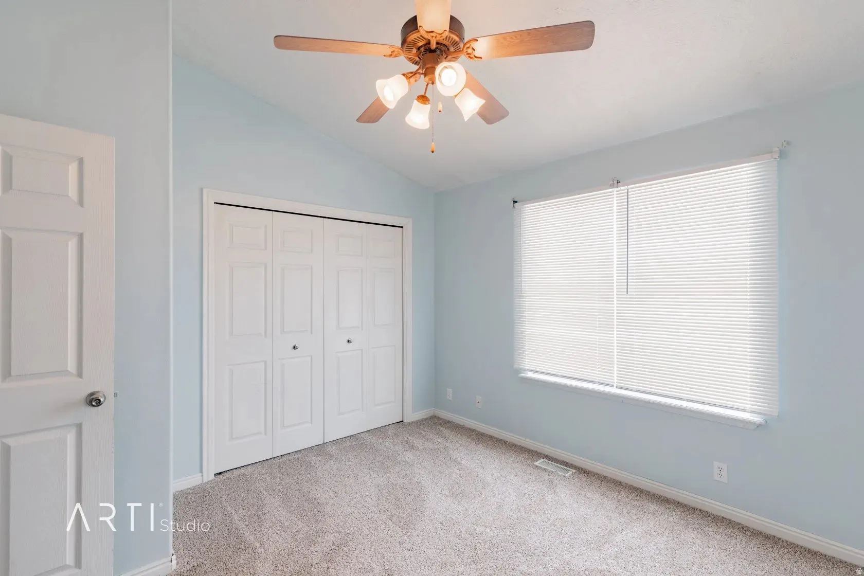 Vaulted ceiling with a ceiling fan, light blue wall paint, white paneled door, and a white bi-fold closet