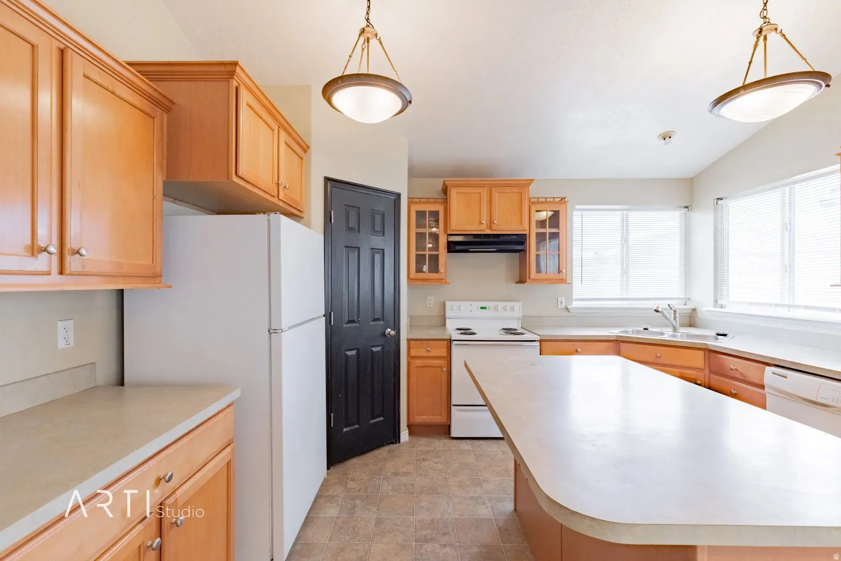 Kitchen featuring light wood cabinetry, a central island with a solid surface countertop, white appliances, and dual pendant lighting