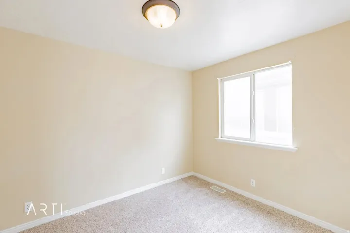 Neutral wall color, carpeted flooring, and a single window with white trim