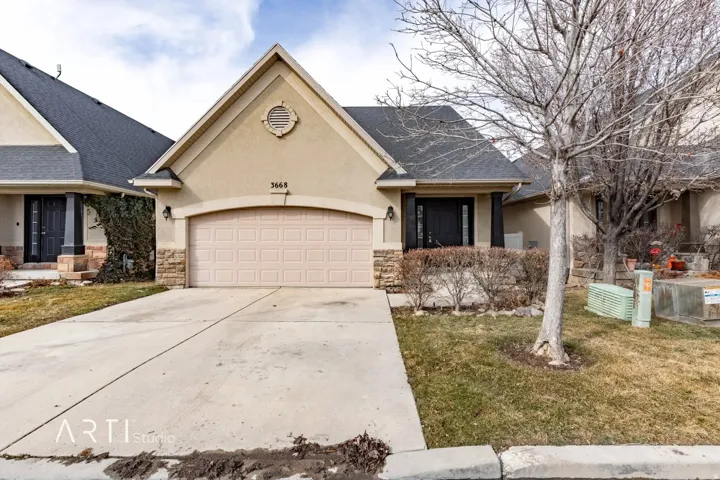 Siding exterior with stone accents, a multi-pane front door, a two-car garage, and a concrete driveway
