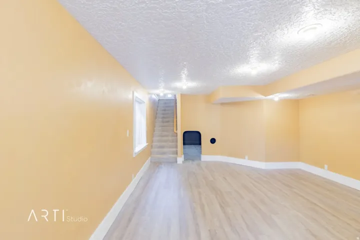 Spacious room featuring wood-finish flooring, recessed lighting, and a window for natural illumination