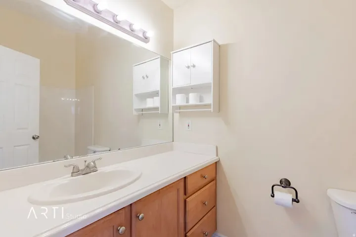 Vanity with wood-finish cabinetry, integrated sink, and chrome faucet