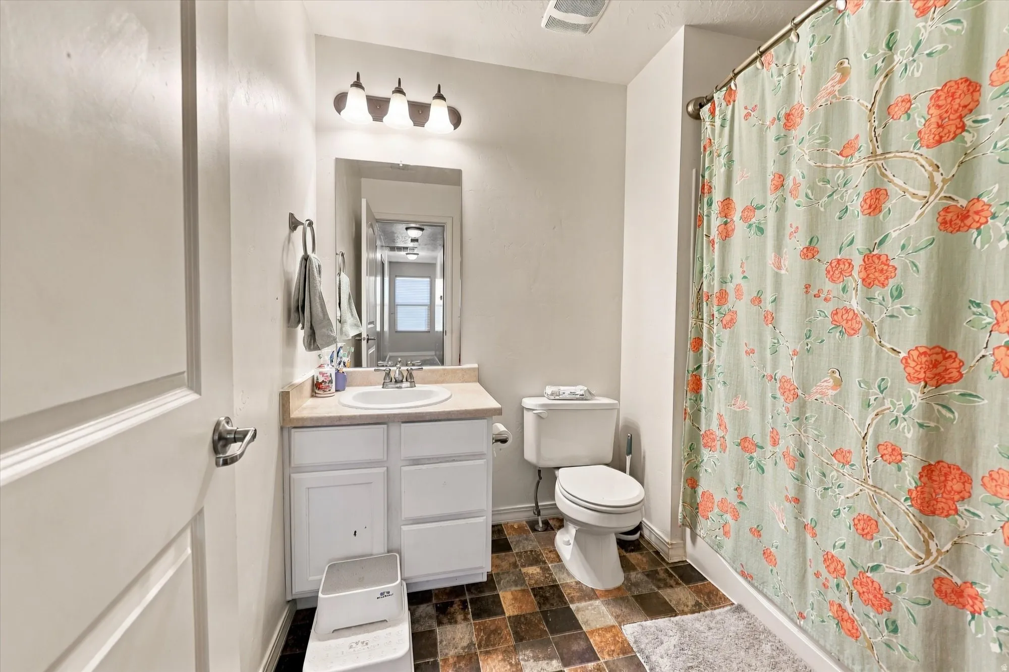 White vanity with a laminate countertop, undermount sink, and chrome faucet