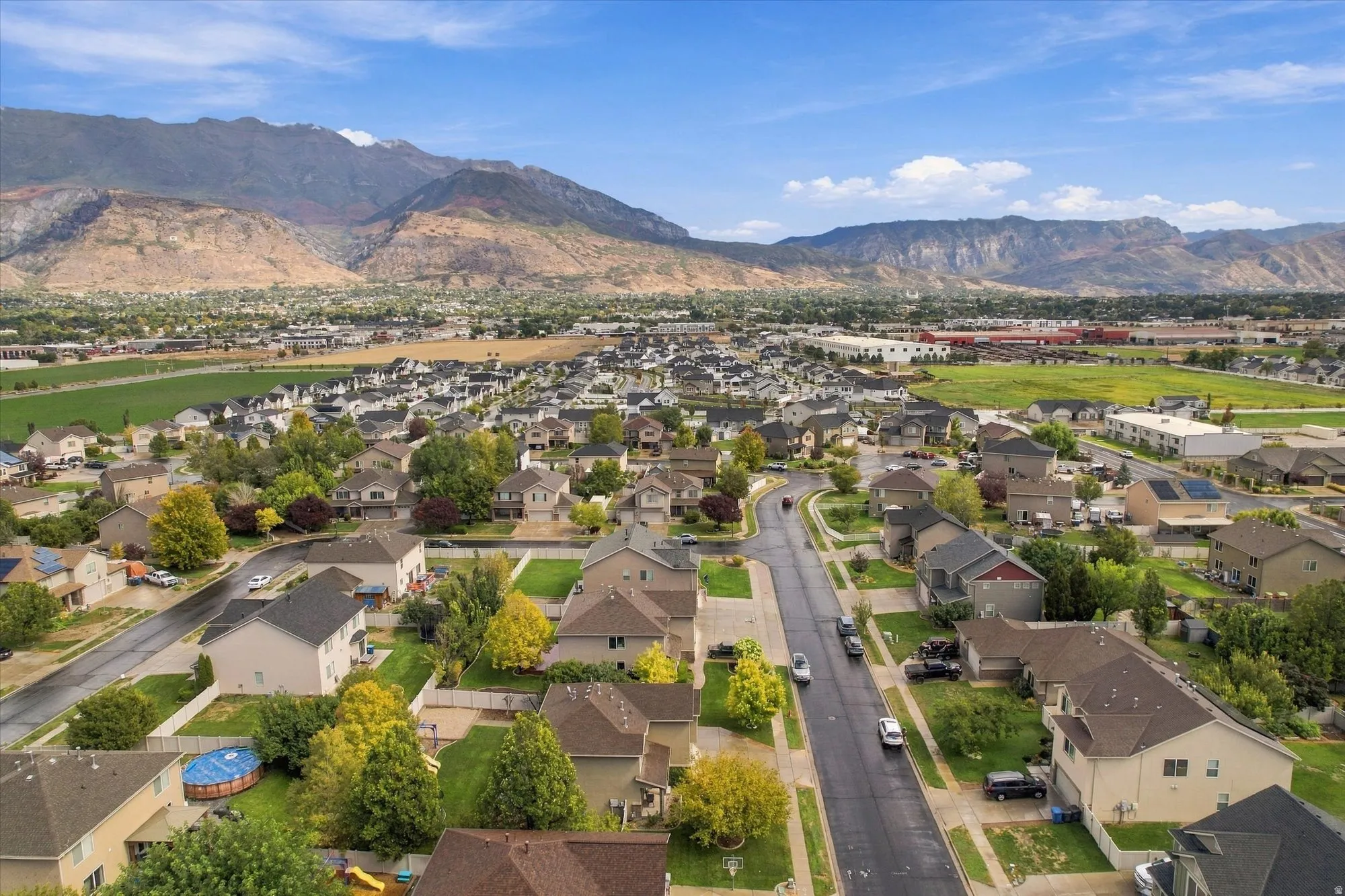 Residential neighborhood with a curved street layout, mature trees, and mountainous scenery