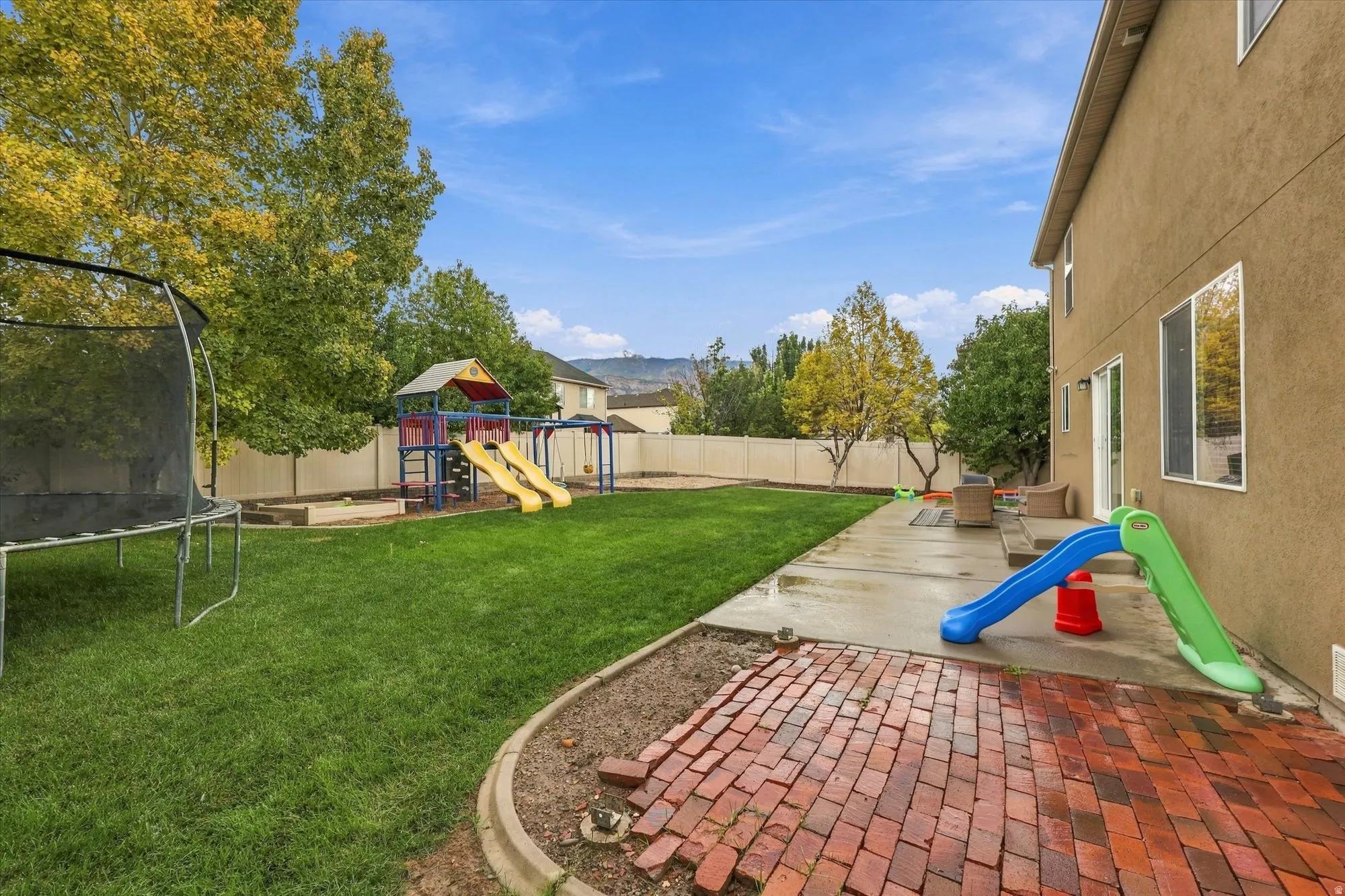 Expansive backyard with a manicured lawn, brick paver patio, concrete patio, and a privacy fence