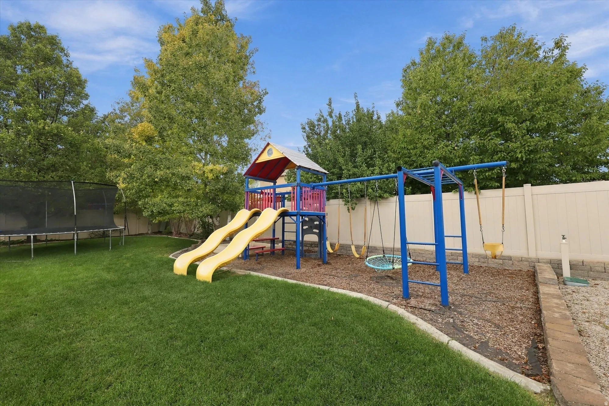 Expansive backyard featuring a manicured lawn, established trees, and a privacy fence