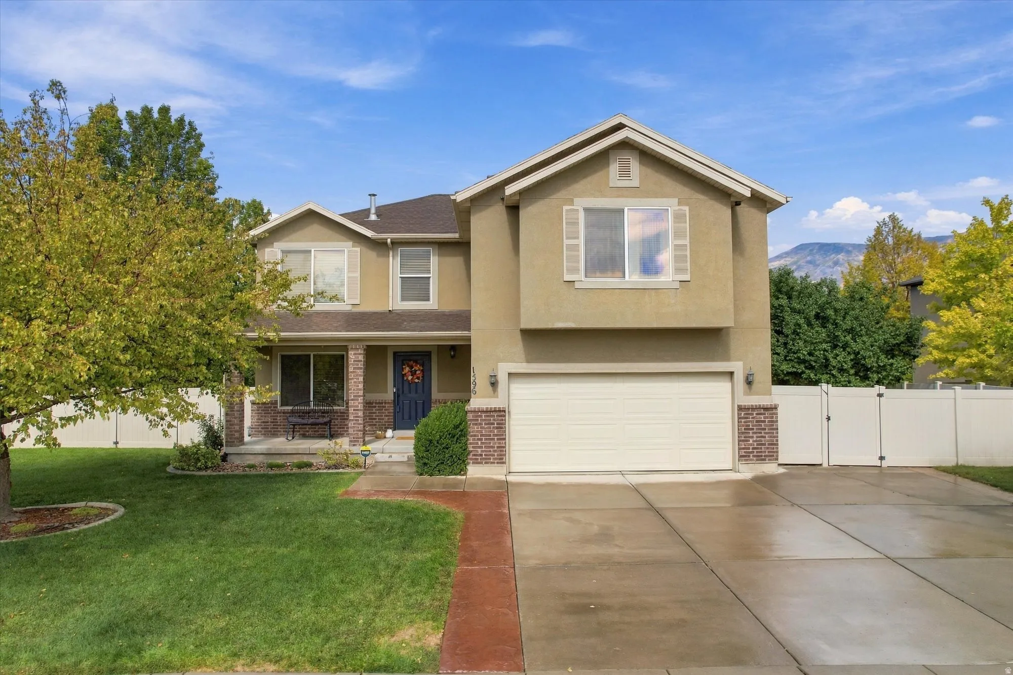 Stucco and brick facade with a two-car garage, established front landscaping, and a covered entry