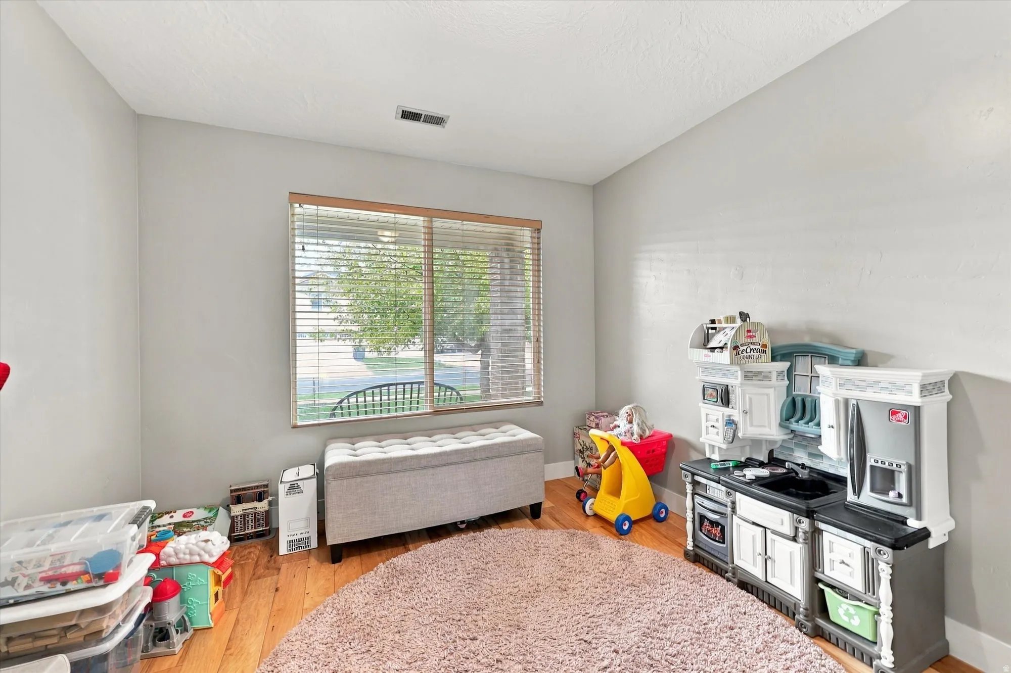 Recessed window with wood-finish blinds, light gray wall paint, and wood-finish flooring