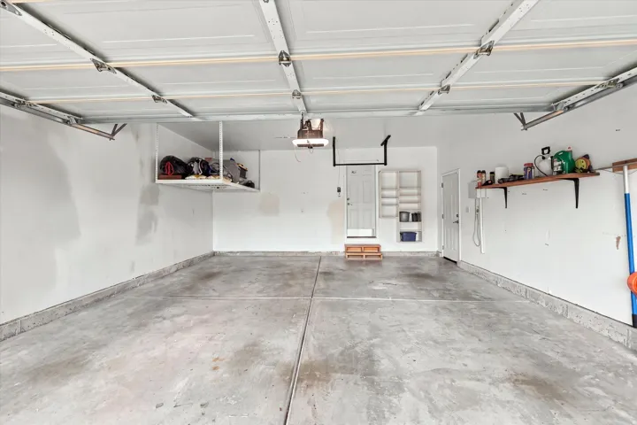Concrete flooring, overhead garage door, built-in shelving, wall-mounted shelving, overhead storage unit