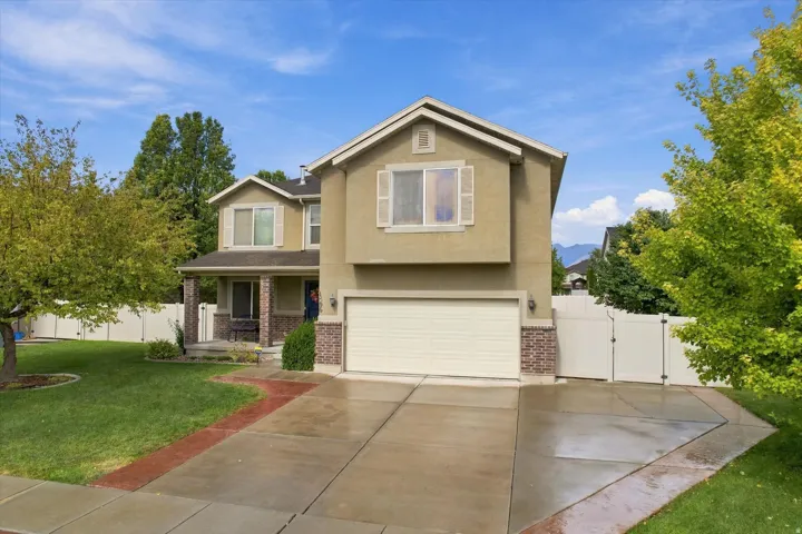 Two-story residence featuring a stucco exterior with brick accents, an integrated garage, a covered entry porch, and a fenced side yard