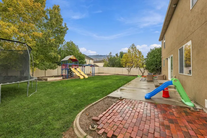 Expansive backyard with a manicured lawn, brick paver patio, concrete patio, and a privacy fence