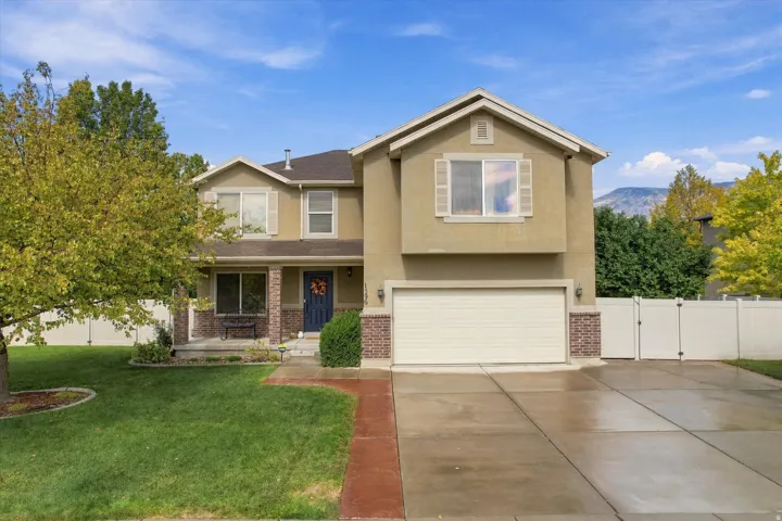 Stucco and brick facade with a two-car garage, established front landscaping, and a covered entry