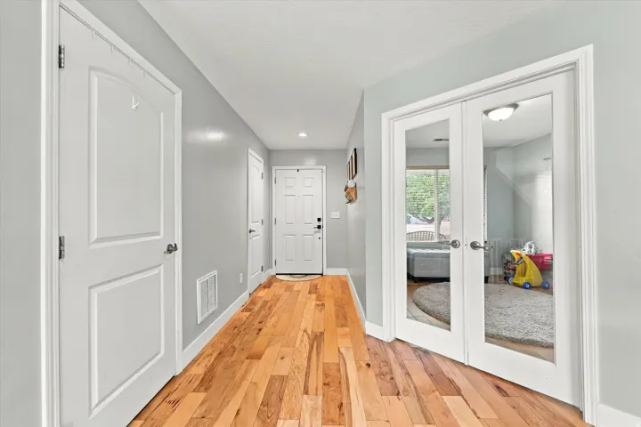 Hardwood flooring, painted walls, white trim, and white doors