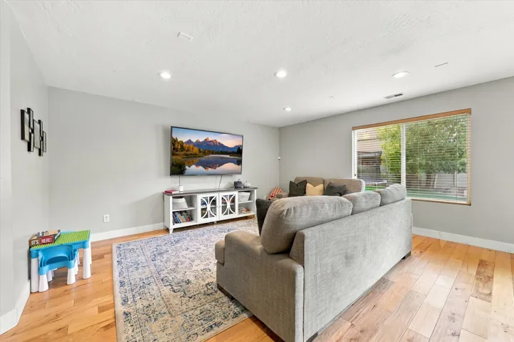 Recessed lighting, wood-finish flooring, and a large window with horizontal blinds