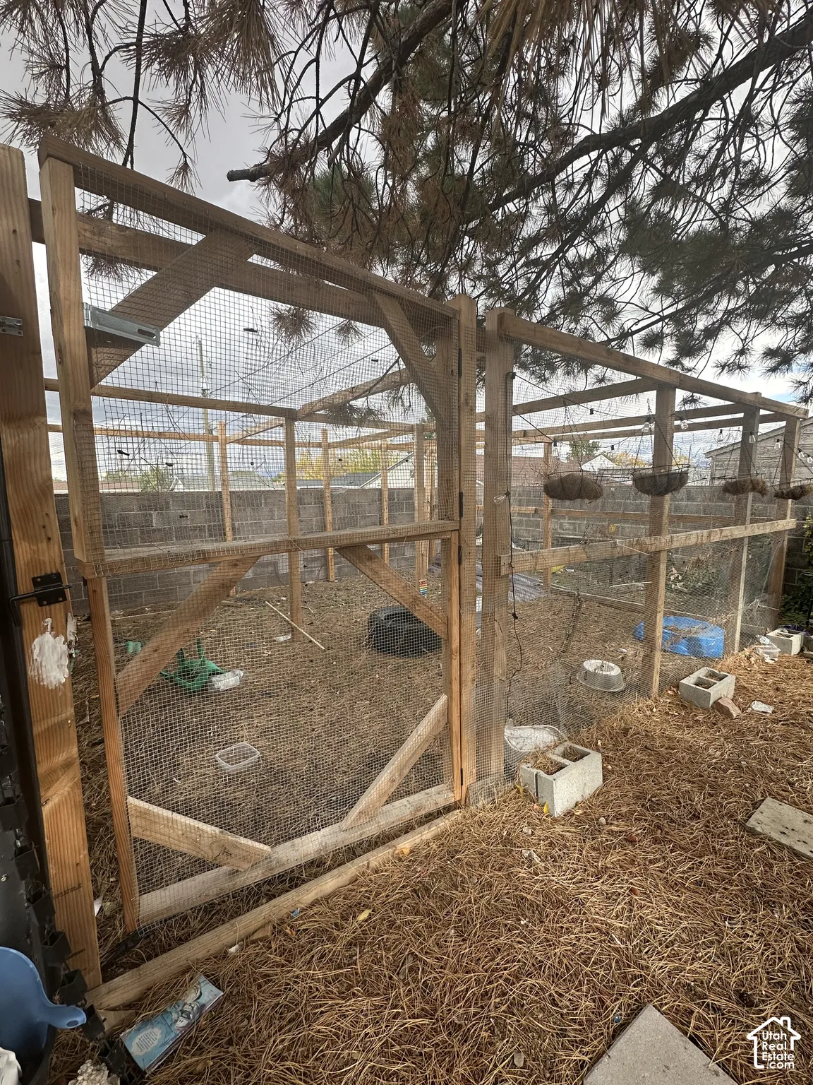 Enclosed outdoor structure featuring a wood frame, wire mesh fencing, and a concrete block perimeter wall