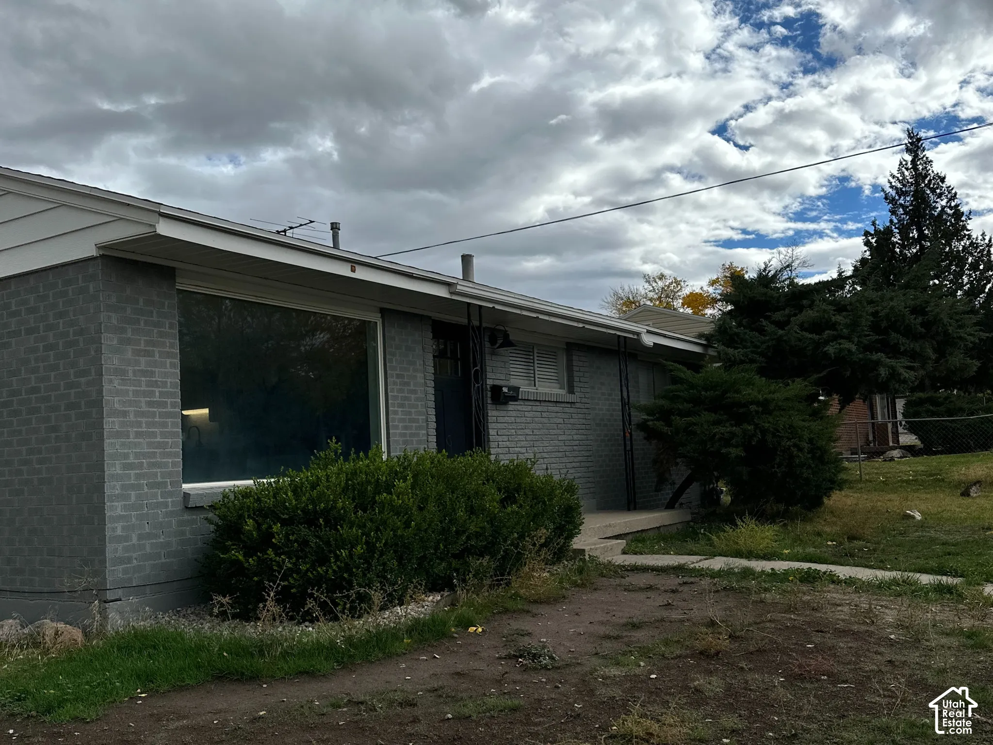 Single-story exterior featuring painted masonry siding, a wide front-facing picture window, and a concrete walkway
