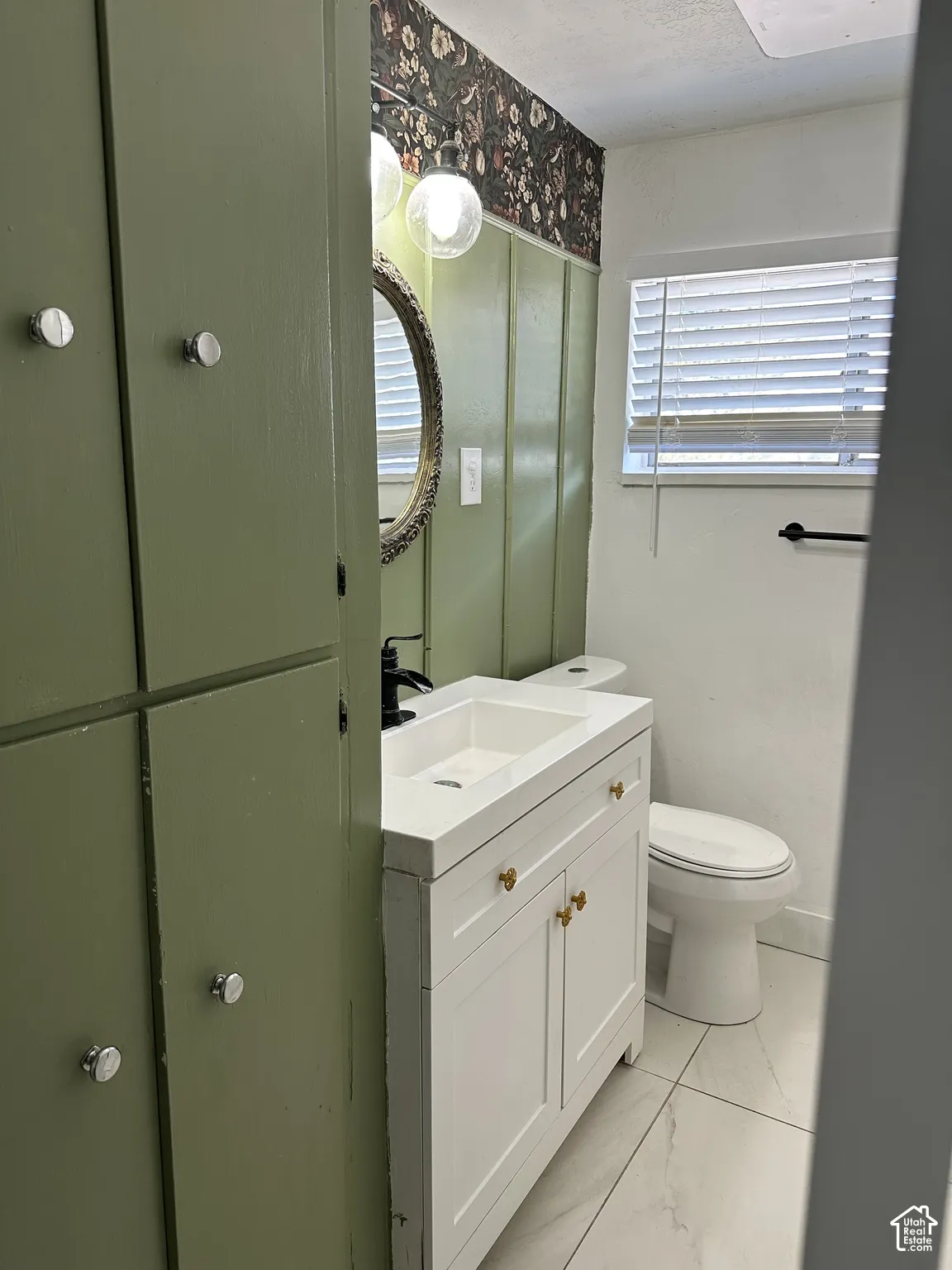 White vanity with gold-tone hardware, integrated sink, and matte black faucet