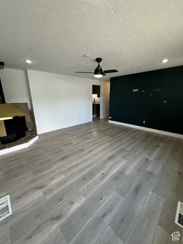 Wood-finish flooring, recessed lighting, ceiling fan, and a built-in fireplace with a hearth