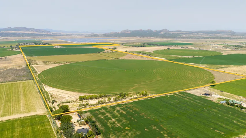 Expansive agricultural land featuring cultivated fields, a circular irrigation pattern, and distant mountain backdrops